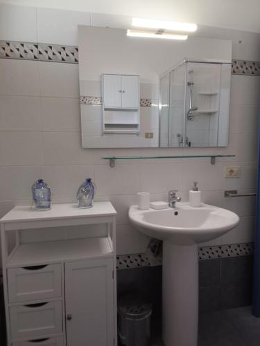 a white bathroom with a sink and a mirror at Sole e relax da Michelle in Anzio