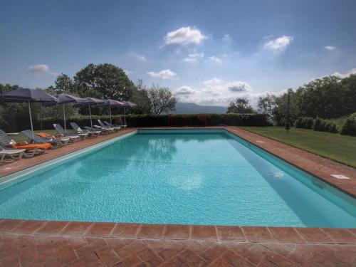 a swimming pool with chairs and umbrellas at Serene Farmhouse in Proceno with Swimming Pool in Proceno