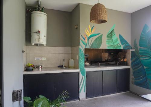 a kitchen with blue cabinets and a mural of leaves at Casa Los Nogales in Roldán