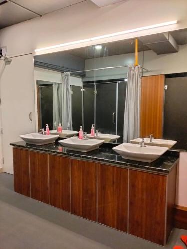 a row of sinks in a bathroom with mirrors at Ivory Inn Dormitory in Mangalore