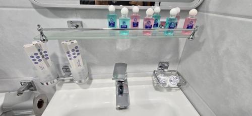 a bathroom sink with toothbrushes on a shelf above it at Zumrad Boutique Hotel in Bukhara