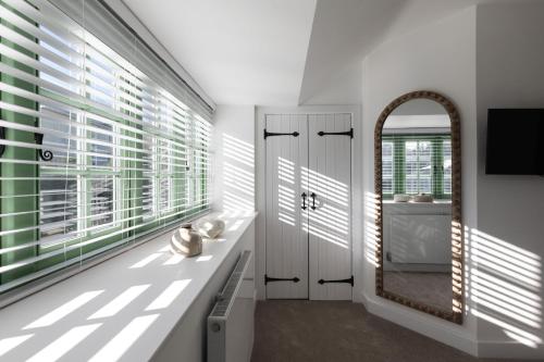 a bathroom with white walls and windows with a mirror at Sunray Cottage in Weymouth