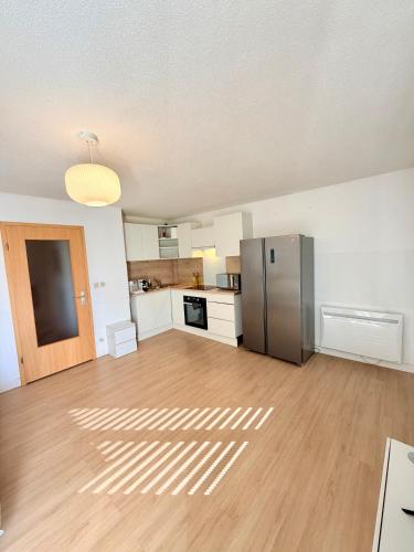an empty room with a kitchen with a refrigerator at Appartement cosy à 10 min de Strasbourg - Bischheim in Bischheim