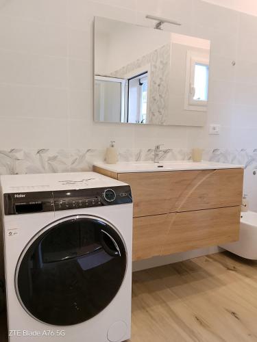a white kitchen with a washer and a sink at casa vacanza La Palma Rossa Taranto in Taranto