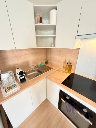 a small kitchen with white cabinets and a sink at Appartement cosy à 10 min de Strasbourg - Bischheim in Bischheim