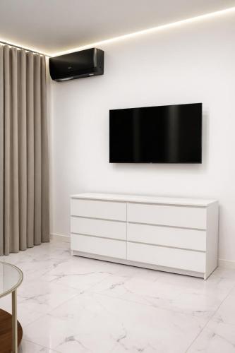 a living room with a television on a white wall at Luksusowy Apartament W Centrum Gdańska in Gdańsk