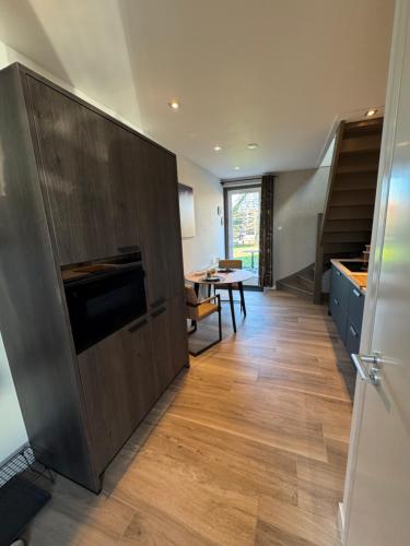 a kitchen with wooden cabinets and a dining room at Kustgeluk-Luxe aan Zee, splinternieuw appartement in het hart van Koudekerke in Koudekerke