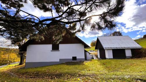 a small white building on a hill with a tree at Chalupa Lindenberg in Jestrabi V Krkonosich