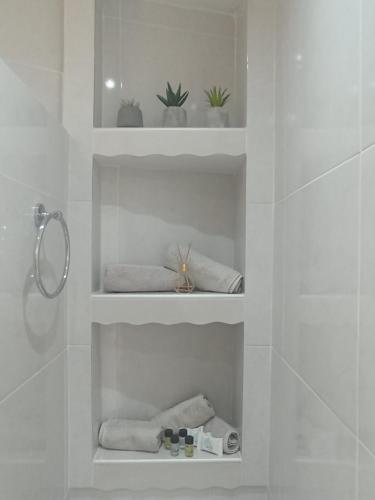 a bathroom with white shelves with plants and towels at Olympos Princess in Olympos