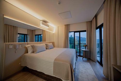 ein Schlafzimmer mit einem großen Bett und einem großen Fenster in der Unterkunft Hotel Cantuccio in Arroio Trinta