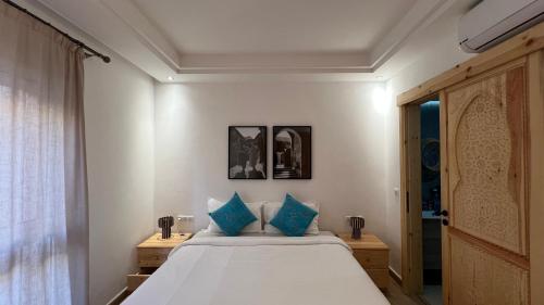 a bedroom with a bed with blue pillows at Strandwohnung Taghazout mit Meerblick, Terrasse, Garten & Pool 2 Min zum Surfspot in Taghazout