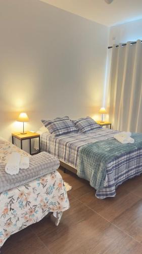 a bedroom with two beds and two tables with lamps at Pouso do Rancho in São José do Barreiro