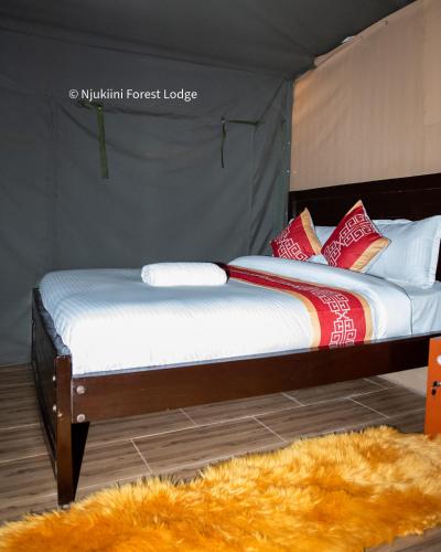 two beds in a tent with a furry rug at Njukiini Forest Lodge in Embu