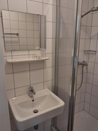 a white bathroom with a sink and a shower at Kolpinghaus Villach in Villach