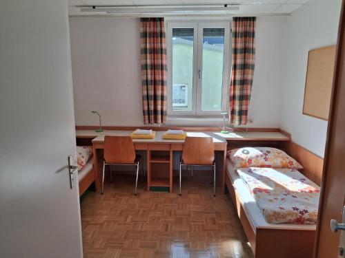 a room with a table and a bed and a table and chairs at Kolpinghaus Villach in Villach