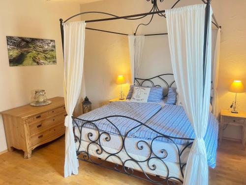 a bedroom with a canopy bed with blue pillows at Chiemsee Beachhouse Apartment in Bernau am Chiemsee