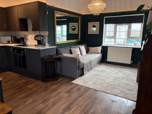 a living room with a couch and a kitchen at Little Yacht Inn in Penzance