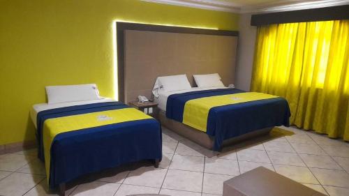 two beds in a room with yellow and blue at Autohotel Punto de Descanso Cordoba in Córdoba