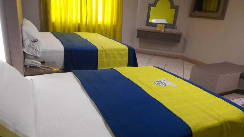 two beds in a room with yellow and blue at Autohotel Punto de Descanso Cordoba in Córdoba