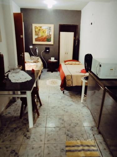 a room with two beds and a table in it at Doce lar in Maringá