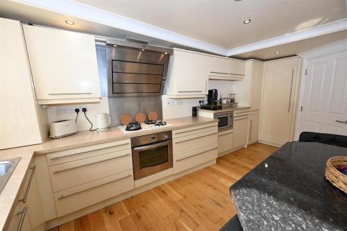 a kitchen with white cabinets and a stove top oven at Church View Richmond - spacious, 2 bed ensuite luxury apartment in town centre in Richmond