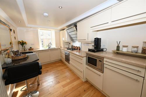 a large kitchen with white appliances and wooden floors at Church View Richmond - spacious, 2 bed ensuite luxury apartment in town centre in Richmond