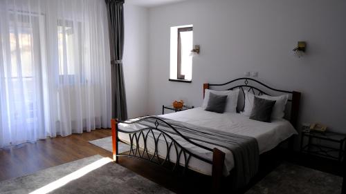 a bedroom with a bed with white sheets and a window at NAD Inn in Sătic