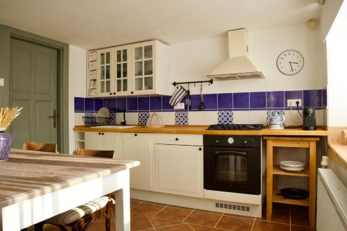 a kitchen with white cabinets and a black stove at Chata Prandorf in Devičany