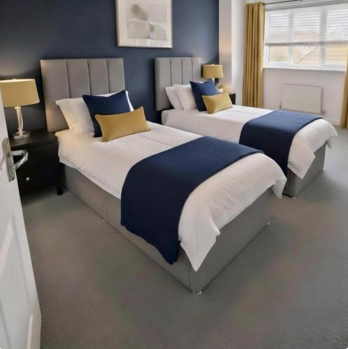 two beds in a bedroom with blue and white at Your Versatile Luxury - Space for All- Sleeps 10 in Bedford