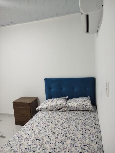 a bed with a blue headboard and a night stand at Santa Marta 1 in Yopal