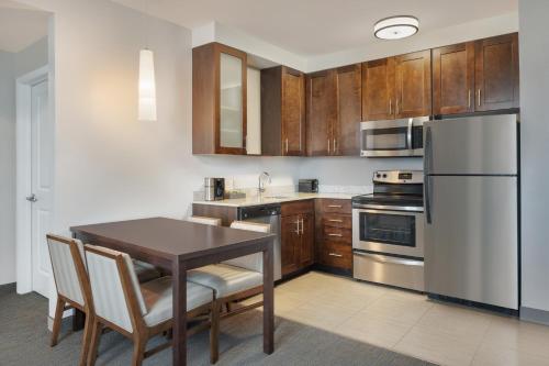a kitchen with a table and a white refrigerator at Residence Inn by Marriott Orlando Downtown in Orlando