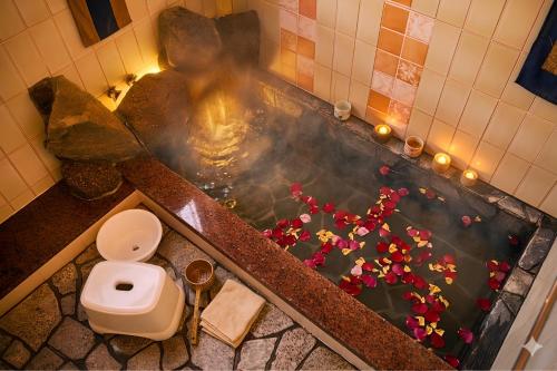 a bath tub with a toilet and flowers in it at 天然温泉付別荘in海友荘 in Shirahama