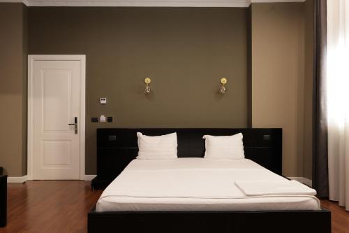 a bedroom with a large bed with white sheets at Monun Boutique Hotel in Tirana