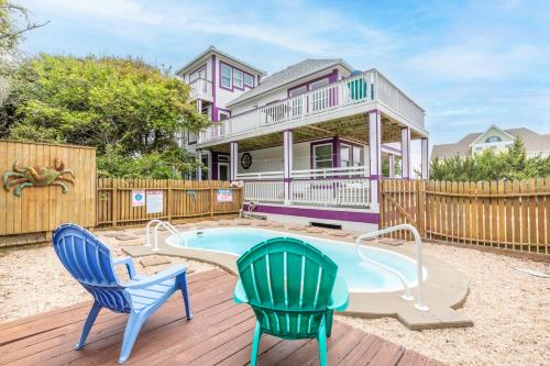 a house with a swimming pool and two chairs at 4751 - Purple Passion in Kitty Hawk Beach