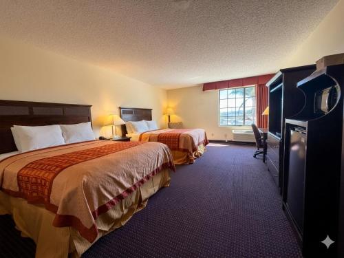a hotel room with two beds and a flat screen tv at Inn of Lompoc in Lompoc