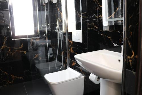 a bathroom with a white toilet and a sink at Hotel Margjokaj2 Velipoje in Velipojë