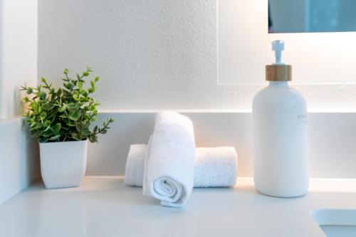 a bathroom counter with towels and a bottle of soap at Luxury 2 Bedroom Residence With Fitness and Outdoor Pool in Los Angeles