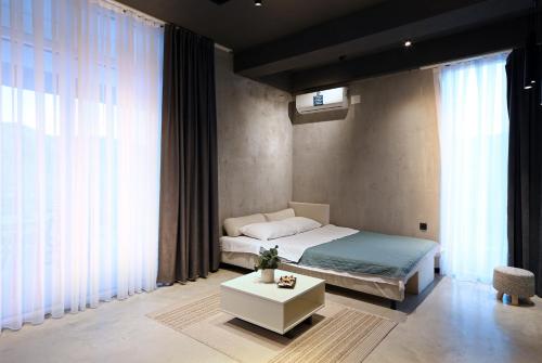 a bedroom with a bed and a table and windows at Tashev Apartments in Veles