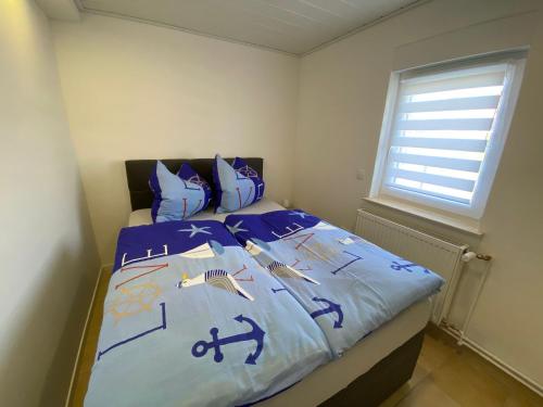 ein Schlafzimmer mit einem Bett mit blauer Bettwäsche und einem Fenster in der Unterkunft Beetzseeperle in Brandenburg an der Havel