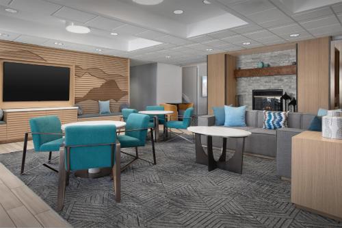a waiting room with a couch and tables and a tv at Homewood Suites by Hilton Colorado Springs North USAFA in Colorado Springs