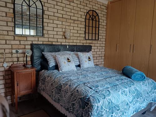 a bedroom with a bed and a brick wall at IVCA Cottage in Addo