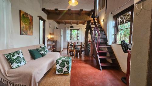a living room with a couch and a spiral staircase at Casas Vila Encantada Refúgio, conforto e natureza, apenas 2 min da avenida in Alto Paraíso de Goiás