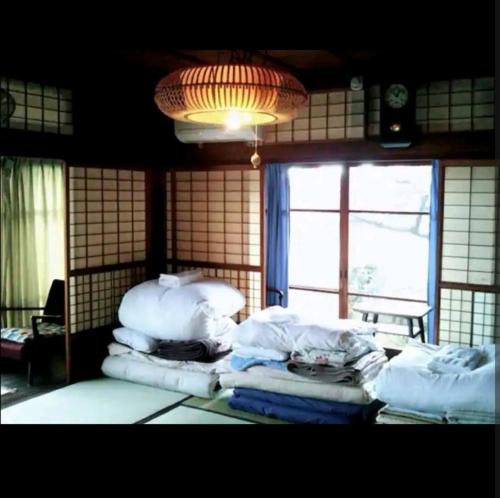 a room with a pile of white pillows and a window at q 2603 Onomichi Tea Celemony Villa in Onomichi