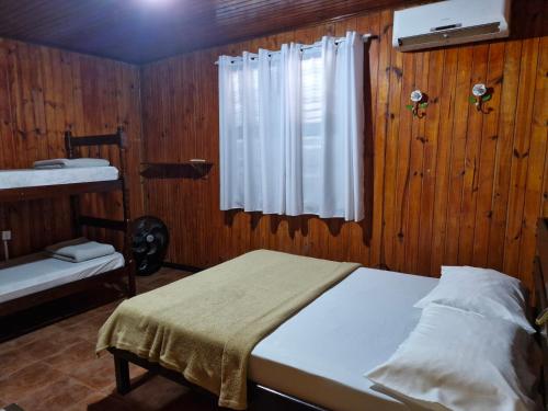 a bedroom with a bed and a window in a room at Wood house casa privada in Abraão