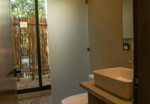 a bathroom with a sink and a toilet and a window at Casa Edén in Xpu Ha