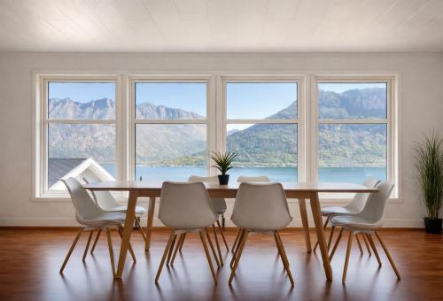 a dining room with a table and chairs and windows at Spacious Waterfront Gem - Panoramic View - Terrace in Fjordgård
