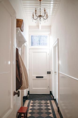 a hallway with a white door and a chandelier at B&B Chez Nous in Geesteren