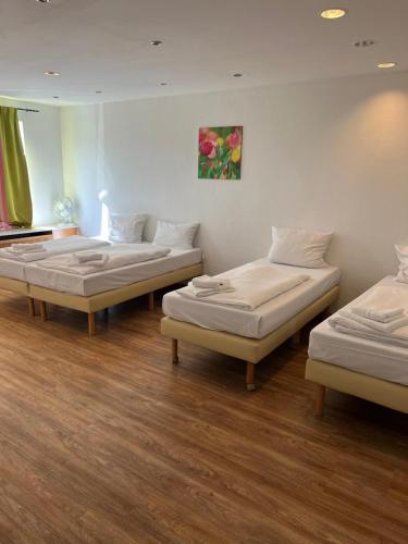 three beds in a room with wooden floors at Pension Passion Julie in Berlin
