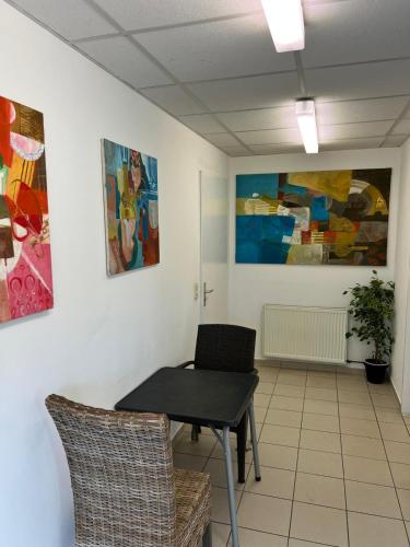 a room with a table and chairs and paintings at Pension Passion Julie in Berlin