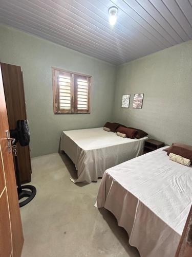 a room with two beds and a window at Chalé 1 - próximo à igreja do céu in Viçosa do Ceará